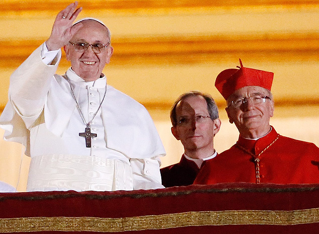 O papa Francisco (de branco) saúda fiéis na praça de São Pedro; à sua esquerda, o brasileiro dom Claudio Hummes (de vermelho)