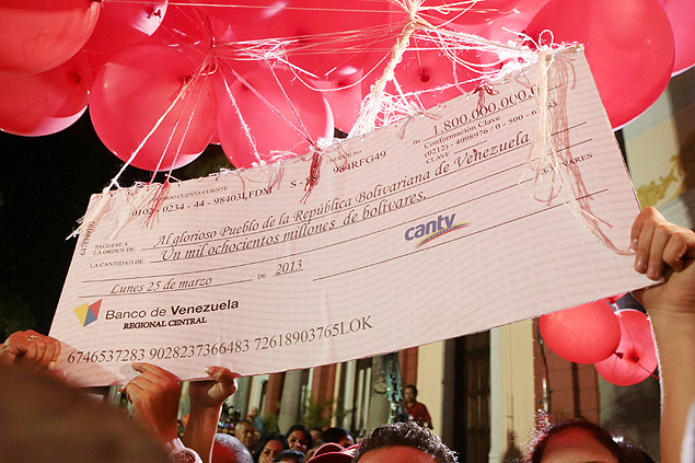 Cartaz que representa um cheque referente aos dividendos de empresa estatizada por Chvez  amarrado a bales e lanado no cu de Caracas