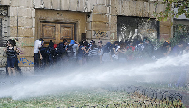 Estudantes tentam fugir de canho d'gua durante protesto por reformas na educao em Santiago, no Chile, nesta quinta 
