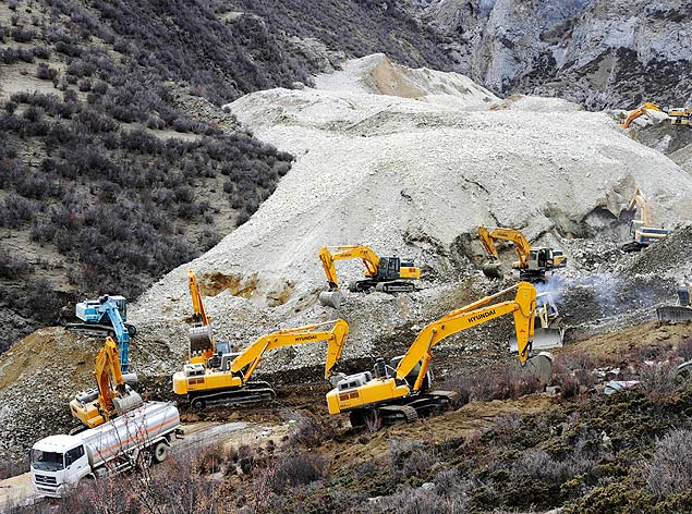 Escavadeiras tentam tirar parte da terra que soterrou 83 operários de uma mina de ouro perto de Lhasa, capital do Tibete