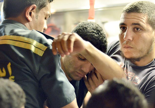 Jovem é amparado por colegas e paramédicos ao lado de uma ambulância após ser intoxicado em universidade no Cairo