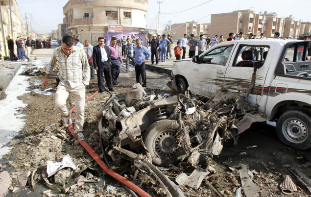 Homem passa por carro destrudo aps exploso em Kirkuk; srie de ataques deixou ao menos 13 mortos e 157 feridos 