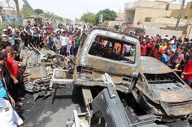 Iraquianos observam veculos queimados em ataque a mercado da Sadr City, em Bagd