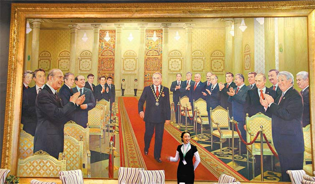 Funcionria posa diante do quadro em que o presidente cazaque, Nursultan Nazarbayev,  saudado por lderes mundiais