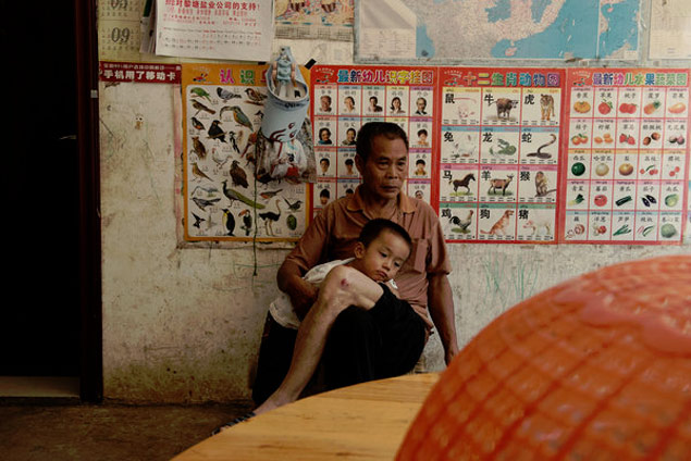 Zhou Mao, com o neto, aguarda noticias do filho, que desapareceu em Gana aps uma onda de represso a garimpos
