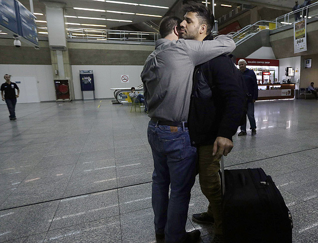 Glenn Greenwald (esq.)abraça o namorado David Miranda após sua chegada ao aeroporto do Rio; Miranda ficou detido por quase 9 horas em Londres, onde fez escala 