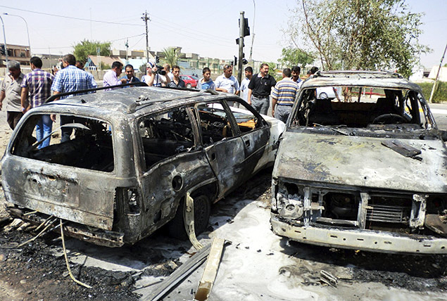 Grupo de civis observa lugar onde um carro-bomba foi detonado, prximo  prdio do governo na cidade de Kirkuk