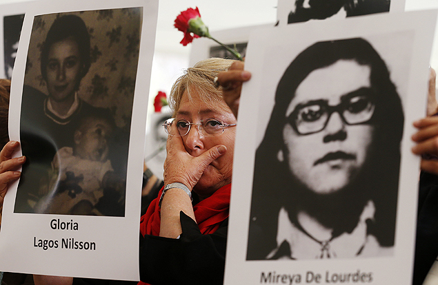 Bachelet segurando fotos de vítimas durante homenagem aos prisioneiros desaparecidos da ditadura, em 10 de setembro de 2013