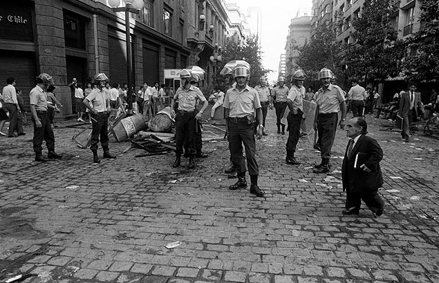 Homem passa por policiais durante protesto nas ruas de Santiago; foto foi chamada de "Davi e Golias" por Claudio Prez