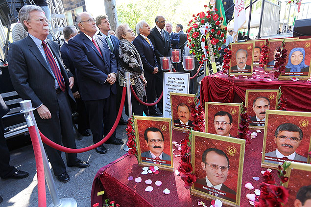 Rudolph Giuliani (2~~o~~ à esquerda) e John Bolton (esquerda) em meio a retratos de dissidentes iranianos mortos em campo de refugiados