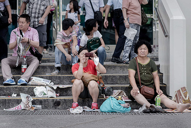 Entre folhas de jornal e plsticos no cho, chineses sentam-se na escadaria de um monumento de Hong Kong