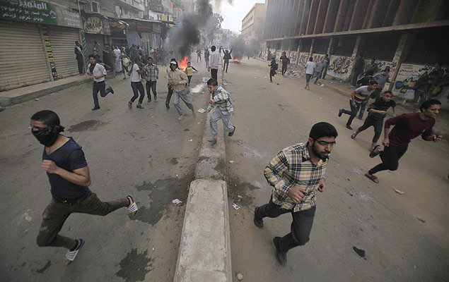 Manifestantes a favor de Mohammed Mursi correm enquanto a polcia usa bombas de gs para dispers-los no sul do Cairo