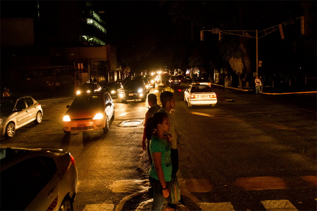 Pedestres andam em rua sem luz durante apago em Caracas, na Venezuela
