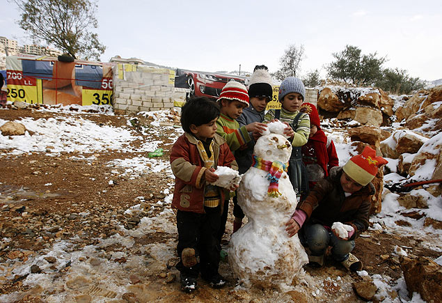 Crianas refugiadas srias fazem boneco de neve em campo na vila de Baaloul; ONU diz que complicou distribuio de ajuda