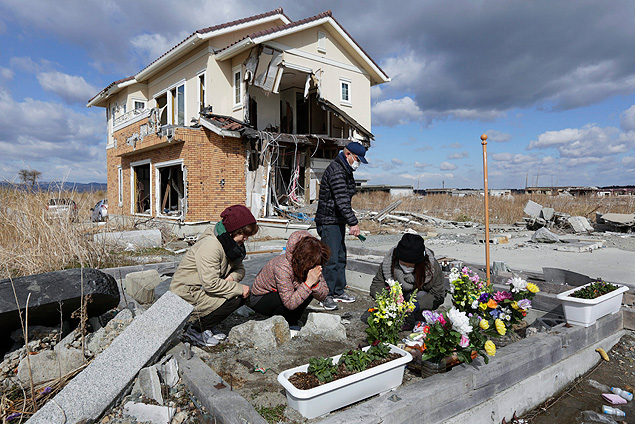 Mulheres rezam por parentes mortos em tragdia de Fukushima, no Japo, em frente a sua antiga casa