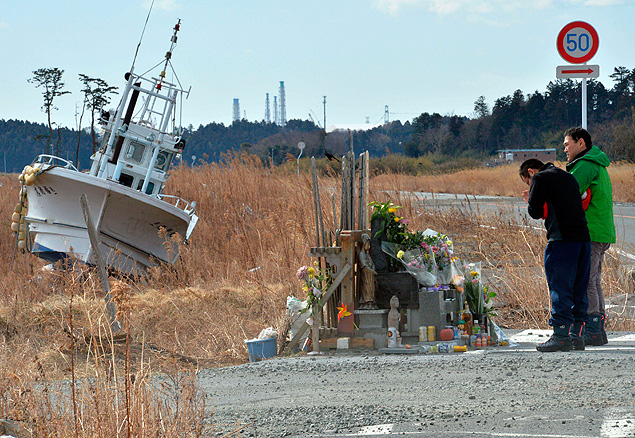 Homens rezam em frente a altar em homenagem aos mortos de Fukushima em local prximo  antiga usina
