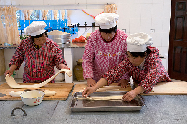 Membros da comunidade Novo Oásis para a Vida, na China, preparam refeição