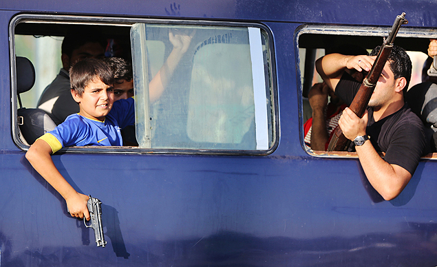 Jovem iraquiano com camiseta do Brasil segura arma em nibus de voluntrios do exrcito iraquiano