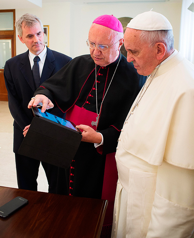 Arcebispo Claudio Mari Celli mostra notcias em tablet ao papa Francisco
