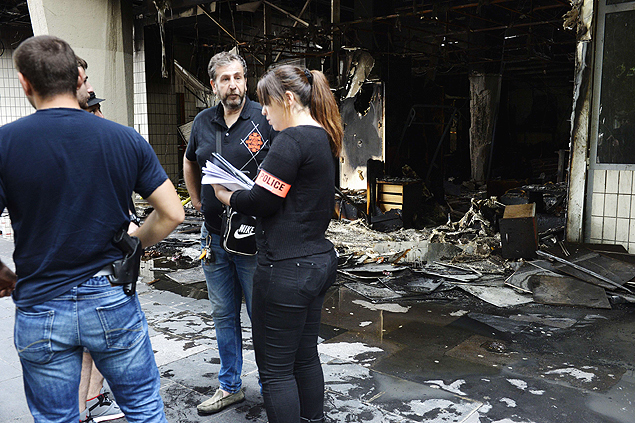 Policiais investigam local incendiado durante manifestao em Sarcelles, na Frana