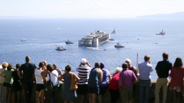 Pessoas observam navio Costa Concordia sendo rebocado do litoral da ilha do Giglio para porto na cidade de Gnova