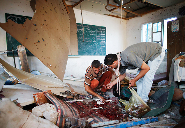 Homens recolhem destroos na escola da ONU em Jabaliya, faixa de Gaza, aps ataque israelense