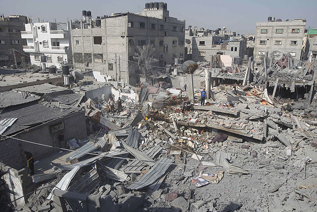 Palestinos inspecionam os restos de um prdio que foi atingido por um ataque de Israel em Rafah
