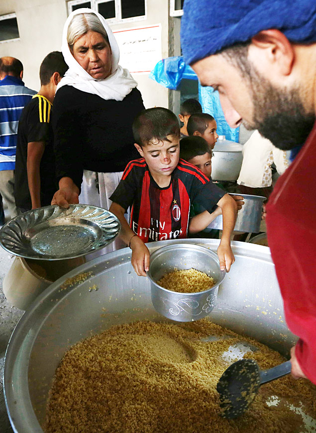 Refugiados da etnia yazidi que fugiram de Sinjar recebem comida em Dohuk, no norte do Iraque