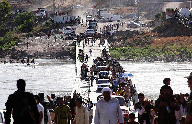 Refugiados yazidis atravessam rio na fronteira entre o Iraque e a Sria para fugir de conflito
