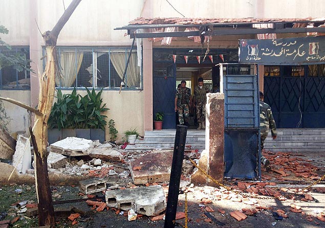 Foras de segurana da Sria inspecionam a escola al-Makhzoumi, em Homs, atingida por uma exploso