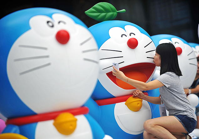 Mulher tira fotos em exibição do mangá Doraemon, no sudoeste da China