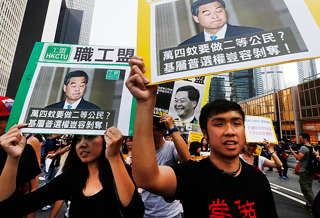 Manifestantes carregam cartazes com foto de Leung Chun-ying em marcha a sua casa