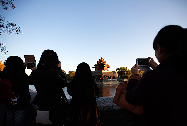 Pessoas fotografam parte da Cidade Proibida vista em um céu sem poluição em Pequim