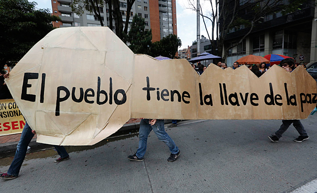 Protesters hold a board in the shape of a key reading "The people has the key to peace" during a demonstration in Bogota November 19, 2014. Hundreds of protesters marched in support of peace negotiations between the Colombian government and the Revolutionary Armed Forces of Colombia (FARC) rebels. The Colombian government has suspended peace talks being held in Cuba until General Ruben Dario Alzate - seized over the weekend as he left a boat in the coastal region of Choco - is freed by the FARC. The standoff has plunged the talks, which marked their second anniversary on Wednesday, into crisis while Latin America's longest-running war, which has killed more than 200,000 people during 50 years, drags on. REUTERS/John Vizcaino (COLOMBIA - Tags: POLITICS CIVIL UNREST) ORG XMIT: JWV01