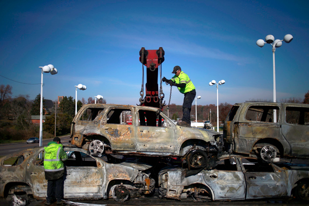 Trabalhadores colocam sobre caminho carros queimados durante protestos em Ferguson