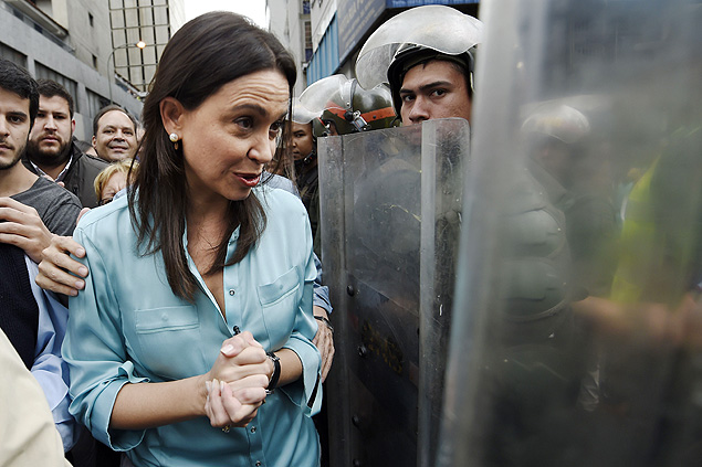 Opositora venezuelana Mara Corina Machado caminha perto de policiais em Caracas
