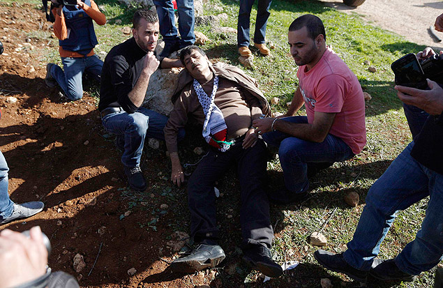 Palestinos ajudam o ministro Ziad Abu Ein aps ele ter sido atingido por soldados israelenses