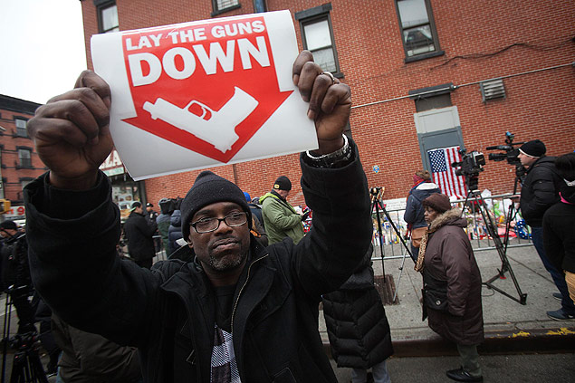 Homem segura placa contra violncia em local onde policiais foram mortos, no Brooklyn