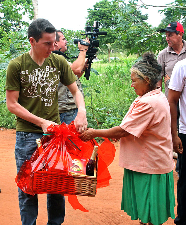 Brasileiro Arlan Fick (esq.) entrega ceta de Natal para moradora de Nueva Fortuna, Paraguai