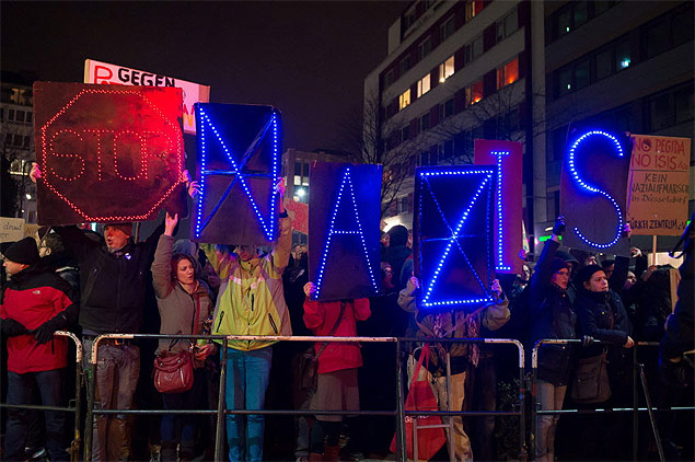Manifestantes seguram placas iluminadas onde se l "parem nazistas", em Dusseldorf, na Alemanha.