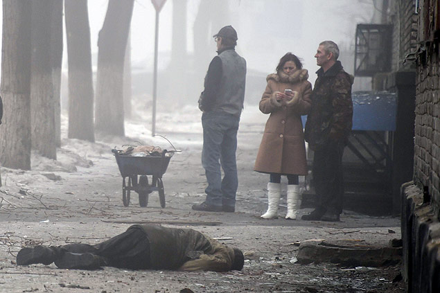 Pessoas observam homem morto no distrito de Kuibuishev, em Donetsk
