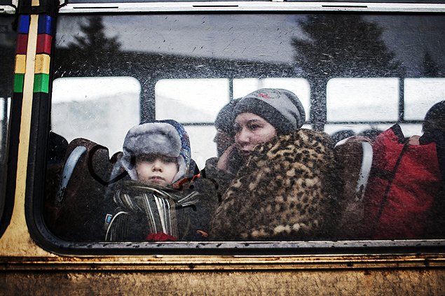 Mulher e garoto esperam em nibus que deixa cidade de Debaltseve, na regio de Donetsk