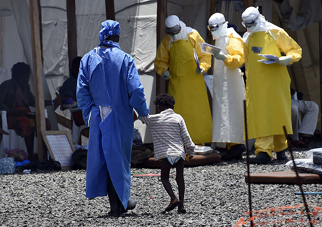 Enfermeira caminha com criana contaminada pelo ebola em centro de tratamento em Monrvia, em setembro