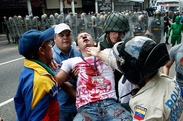 Estudante opositor  socorrido por amigos e policiais aps ser atingido em protesto em San Cristbal. na Venezuela