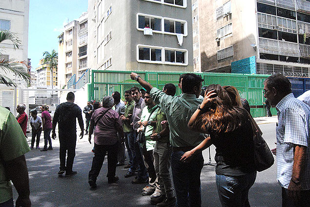 Pessoas observam prdio onde fica a sede do Copei invadida nesta segunda em Caracas