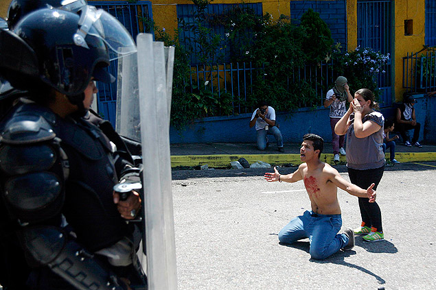 Com sangue no peito, jovem se ajoelha diante de policiais aps a morte do estudante Kluiverth Roa, em San Cristbal (Venezuela)