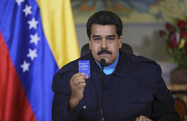 Nicolas Maduro holds up a book of the country's constitution as he speaks during a national TV broadcast in Caracas 