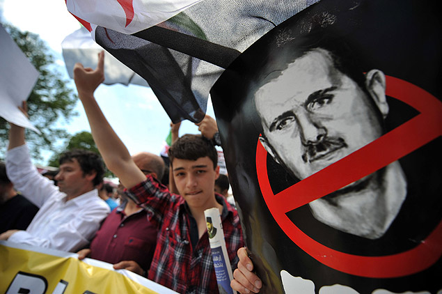 Manifestantes em Istambul gritam palavras de ordem e seguram placa contra o ditador srio Bashar Assad