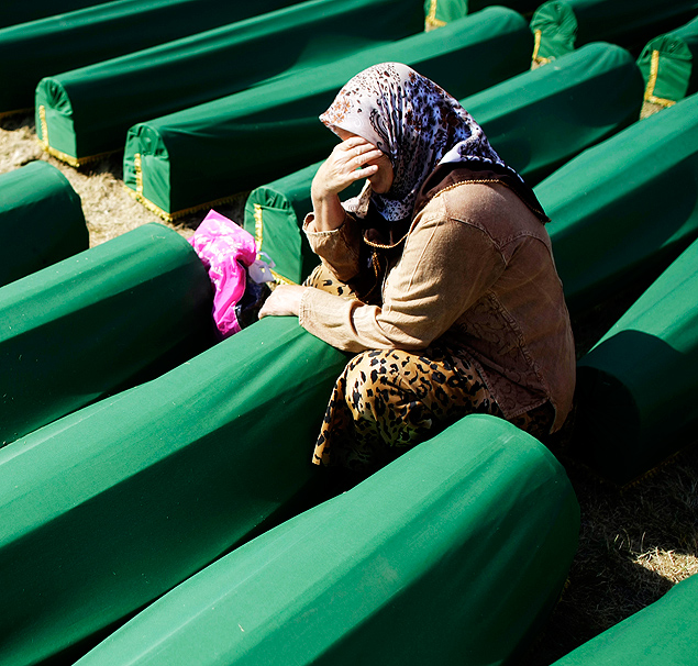 Mulher chora ao lado de caixes de 520 muulmanos mortos no massacre de Srebrenica, em 1995