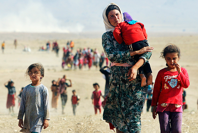 Displaced people from the minority Yazidi sect, fleeing violence from forces loyal to the Islamic State in Sinjar town, walk towards the Syrian border on the outskirts of Sinjar mountain near the Syrian border town of Elierbeh of Al-Hasakah Governorate in this August 11, 2014 file photo. The Islamic State, which had declared a caliphate in parts of Iraq and Syria, prompted tens of thousands of Yazidis and Christians to flee for their lives during their push to within a 30-minute drive of the Kurdish regional capital Arbil. REUTERS/Rodi Said/Files (IRAQ - Tags: POLITICS CIVIL UNREST TPX IMAGES OF THE DAY) ATTENTION EDITORS - THIS PICTURE IS PART OF PACKAGE '30 YEARS OF REUTERS PICTURES' TO FIND ALL 56 IMAGES SEARCH '30 YEARS' ORG XMIT: FTF55